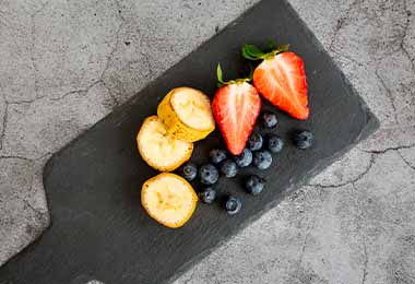 Tabla con fresas, arándanos y bananos en desayuno continental 