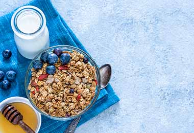 Tazón con granola, fruta, leche y miel en desayuno continental 