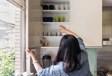 Mujer ordenando su alacena con tazas y vasos