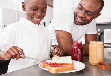 Padre e hijo preparando un sándwich con mermelada casera