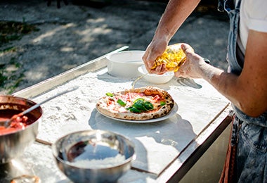 Hombre rociando aceite de oliva en pizza