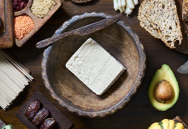 Tofu sólido en una mesa, acompañado de otros alimentos.