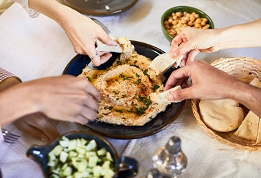 Un grupo de personas compartiendo hummus con pan pita, un clásico de la comida libanesa