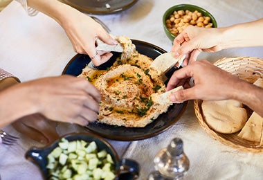 Amigos compartiendo hummus con pan pita, dos comidas mediterráneas