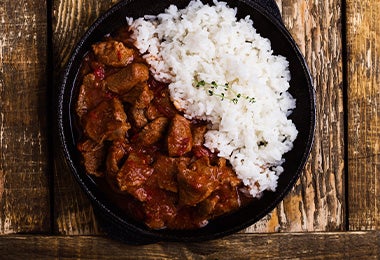 Arroz blanco y carne, comidas fáciles de hacer, servidos en un plato negro