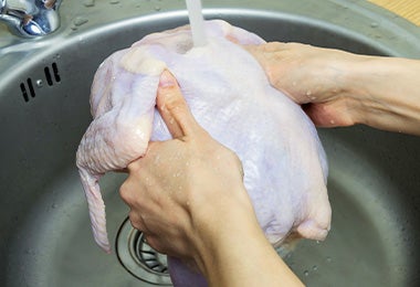 Un pollo entero siendo lavado con agua