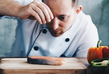 Chef sazonando un pescado antes de hacerlo en la freidora de aire