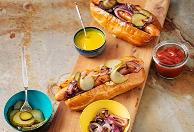  Tabla con hot dogs con salsas kétchup y mostaza