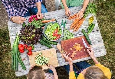 Familia partiendo verduras con diferentes tipos de corte para preparar una ensalada