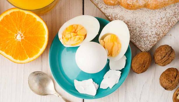 Huevos cocidos, acompañados por jugo de naranja y un croissant.