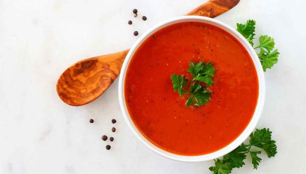 Crema de tomate con perejil, una de las recetas más famosas, servida con una cuchara de madera