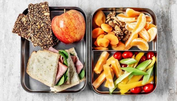 Comida para viaje: barras de cereal, sándwich, frutas, verduras picadas y frutos secos