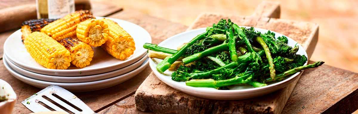 Mazorcas y espárragos sobre una mesa de madera en un asado vegetariano