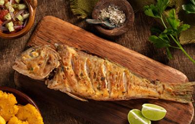 Un pescado frito entero, servido sobre una tabla y acompañado con limón. Un pescado frito entero, servido sobre una tabla y acompañado con limón.