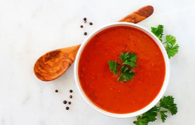 Crema de tomate con perejil, una de las recetas más famosas, servida con una cuchara de madera