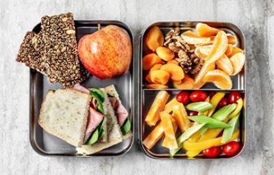 Comida para viaje: barras de cereal, sándwich, frutas, verduras picadas y frutos secos Comida para viaje: barras de cereal, sándwich, frutas, verduras picadas y frutos secos