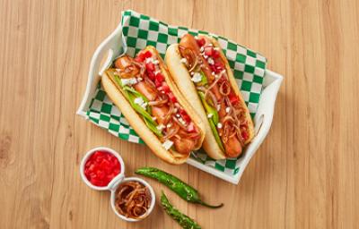 Plato con hot dogs, cebollas caramelizadas, tomates y chiles Plato con hot dogs, cebollas caramelizadas, tomates y chiles