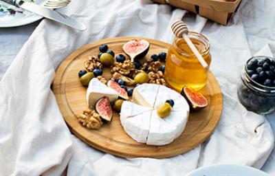 Tabla de quesos con miel, frutas y aceitunas