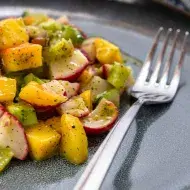 Una ensalada con mango y verduras, con su aderezo.