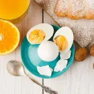 Huevos cocidos, acompañados por jugo de naranja y un croissant.