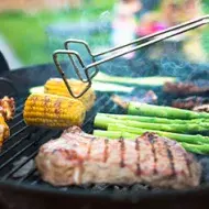 Asado de carne y vegetales, con pinzas para darles vuelta, un utensilio muy importante. 