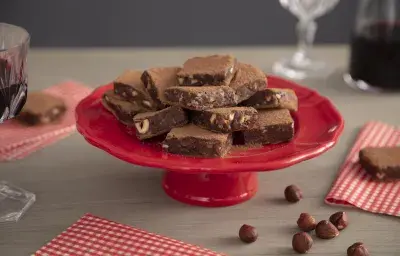 Fotografía en tonos rojos sobre un banco de madera clara con telas a cuadros rojos. En el centro, un puesto de tarta roja con dulces de chocolate trufados. Fotografía en tonos rojos sobre un banco de madera clara con telas a cuadros rojos. En el centro, un puesto de tarta roja con dulces de chocolate trufados.