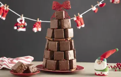 Fotografía en tonos rojos sobre un banco de madera con un pequeño tendedero de Papá Noel, un adorno de Papá Noel en el lado derecho, un plato pequeño con dos bollos y en el centro varios bollos formando un árbol de Navidad. Fotografía en tonos rojos sobre un banco de madera con un pequeño tendedero de Papá Noel, un adorno de Papá Noel en el lado derecho, un plato pequeño con dos bollos y en el centro varios bollos formando un árbol de Navidad.